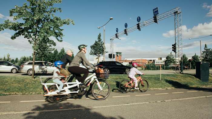 syklister med elsykkel på sykkelvei langs bilveien
