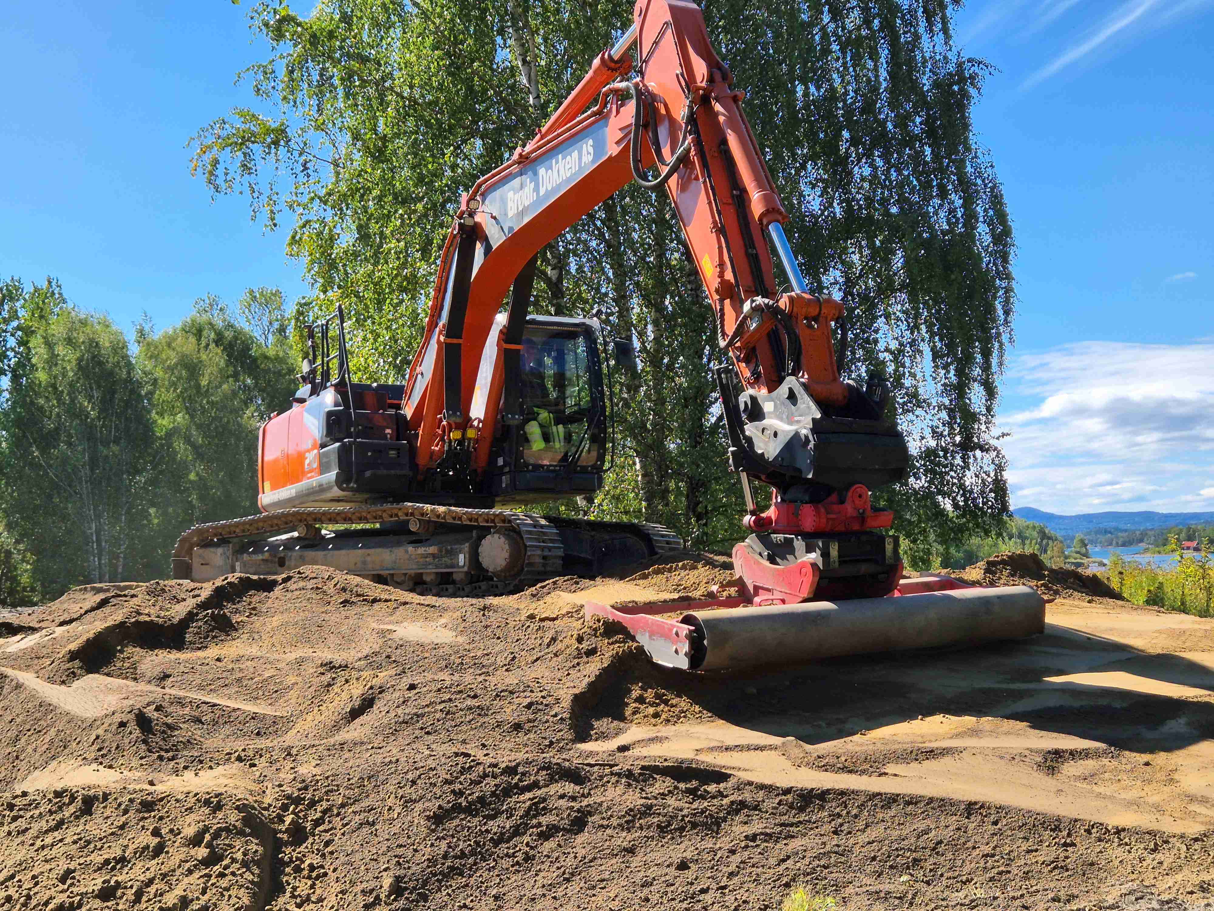 Maskinen har spesialverktøy for å klargjøre jord og sand for såing. Her fordeler og glatter den ut 30 cm med natursand.